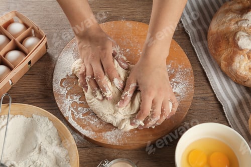 Preview: Female baker preparing bread dough at kitchen table, above view