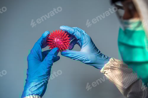 Preview: Medical Professional Holding Spiked Red Sphere Wearing PPE