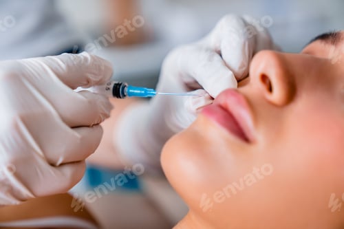 Preview: Close up of hands cosmetologist making injection in lips