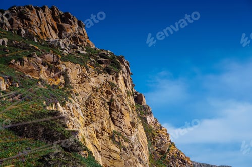 Preview: Beautiful scenic view of high rock mountain cliff peak covered with green grass, trees bushes