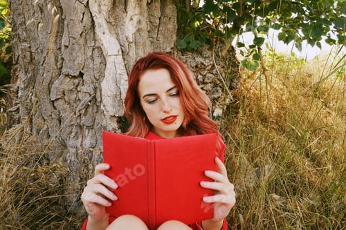 Preview: Young woman reading a red book