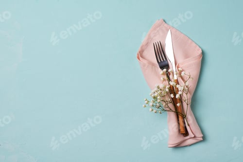 Preview: Tableware setting with fork, knife, napkin and flower on blue background,