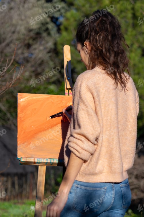 Preview: Woman painting on a canvas with peach fuzz color paint abstract art in nature
