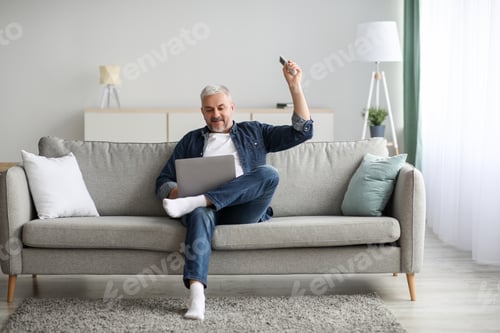 Preview: Relaxed senior man with laptop sitting on couch at home
