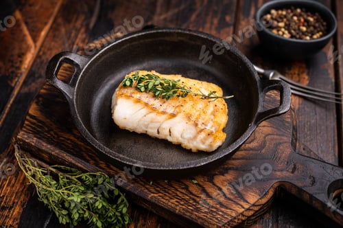 Preview: Roasted cod fish loin fiilet in skillet. Wooden background. top view