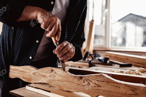 Preview: Hands of a carpenter working with chisel and hammer