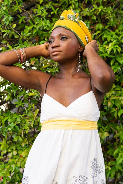 Preview: Confident feminine black lady standing near green bush in park