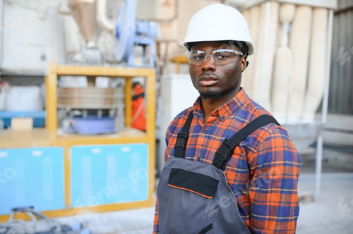 Preview: Portrait of industrial engineer. Smiling factory worker with hard hat standing in factory production