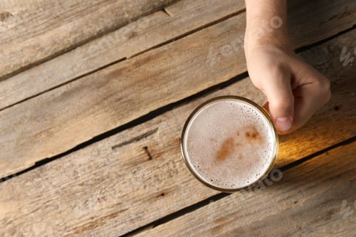 Preview: Man with glass mug of beer at wooden table, top view. Space for text