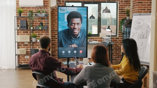 Preview: Group of workers using remote video call to talk to man