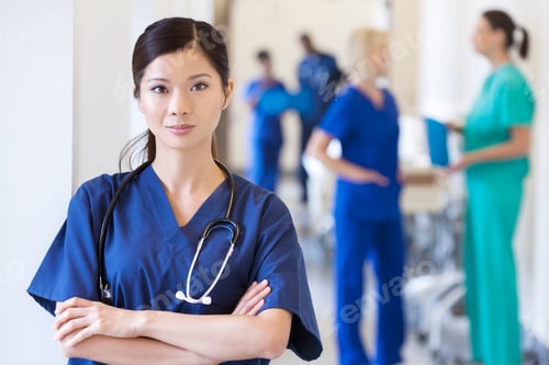 Preview: Portrait of Asian Chinese female nurse wearing scrubs with hospital staff