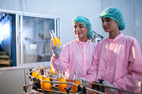 Preview: Asian woman worker is checking product bottles of fruit juice on the production line.