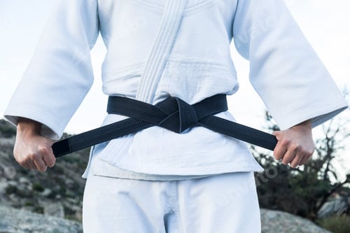 Preview: Man tying his black belt during a martial arts training