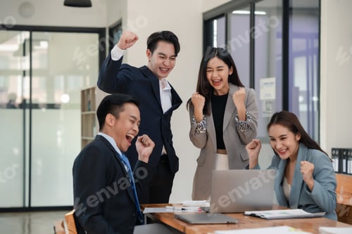 Preview: Asian business team celebrating success with raised fists at office