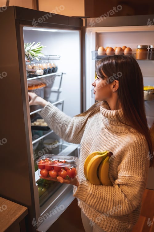 Preview: Woman arranging fresh groceries in freezer