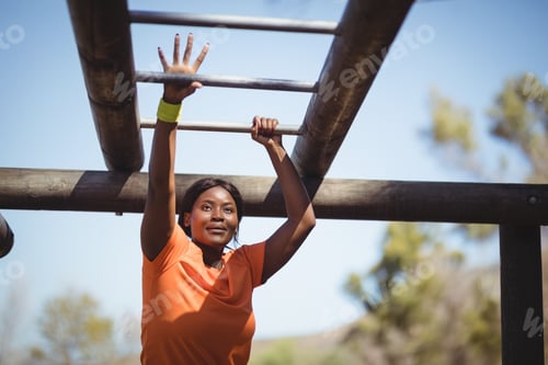 Preview: Determined woman exercising on monkey bar during obstacle course