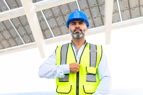 Preview: Hispanic engineer in uniform breathing against modern solar power station
