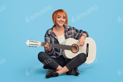 Preview: Excited woman smiling playing guitar