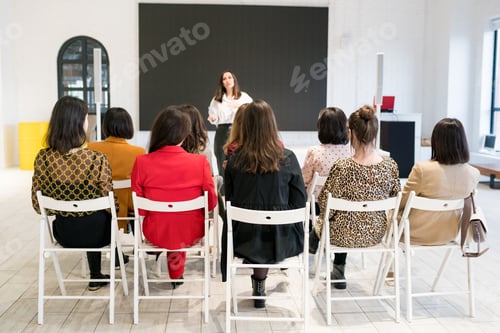 Preview: Rear view of unidentified people listening to coach having speech at business training