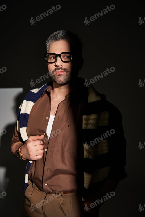 Preview: Stylish man in glasses exudes elegance with trendy outfit in studio setting