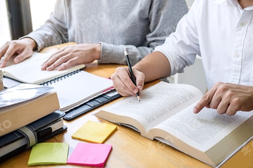 Preview: High school tutor or college student group sitting at desk in library studying and reading