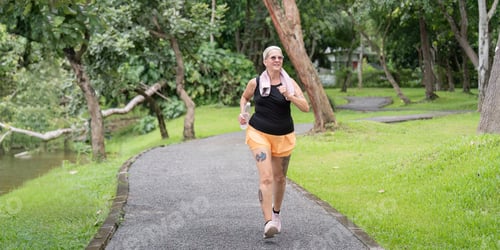Preview: Energetic Older Woman Running in Scenic Park Pathway