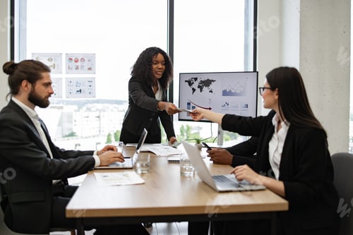 Preview: Businesswoman giving money to employees in boardroom meeting
