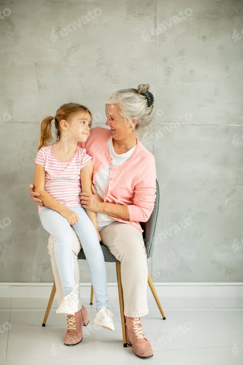 Preview: Little girl with her grandmother sitting in chair by the wall