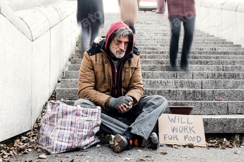 Preview: Homeless beggar man sitting outdoors in city asking for money donation.
