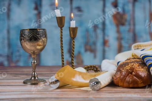 Preview: Shabbat eve table with covered challah bread, candles and cup of wine.