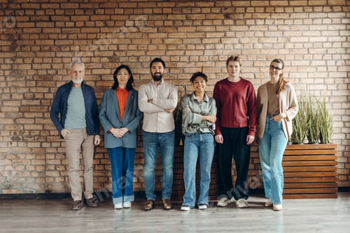 Preview: Startup team posing together in modern office by brick wall