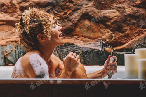 Preview: Beautiful adult woman singing in the shower at home in the bathroom having care and relax