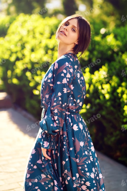 Preview: Beautiful young woman near the blooming spring tree. Attractive girl enjoying her time in park.