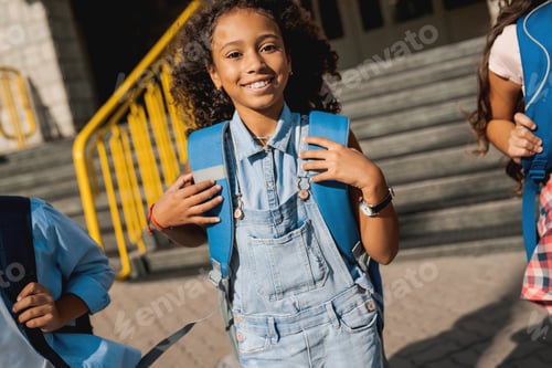 Preview: Group of happy kids with rucksacks walking at school yard