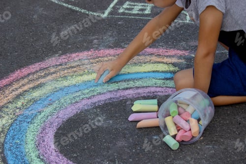 Preview: the boy draws with chalk on the asphalt. Selective focus