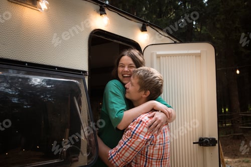 Preview: Happy adult couple having a rest in trailer outdoors