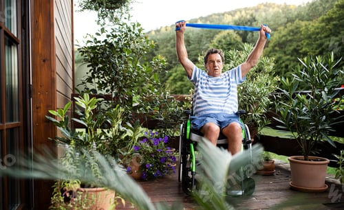 Preview: Senior man in wheelchair doing exercise on terrace.