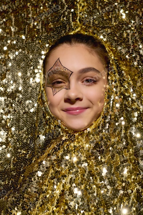 Preview: Cute girl with star face paint shines among golden sequins for Halloween fun