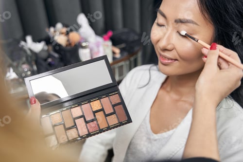 Preview: Unrecognized makeup artist making visage for client in salon