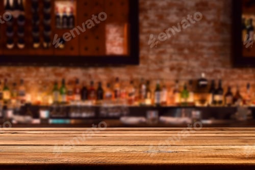 Preview: Empty wooden bar counter with defocused brick wall with liquor bottles