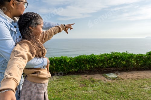 Preview: Mother and daughter pointing at the horizon while enjoying a sunny day by the coast