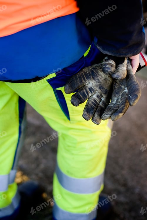 Preview: Low section of construction worker holding messy gloves