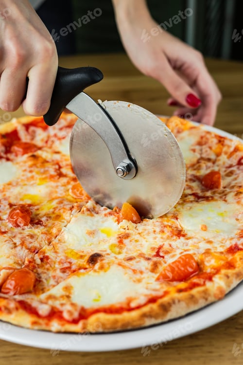 Preview: Close-up of cutting pizza margherita with a pizza cutter