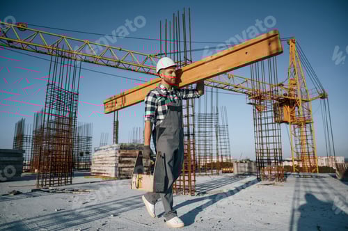 Preview: Holding big wooden piece. Man is working on the construction site at daytime