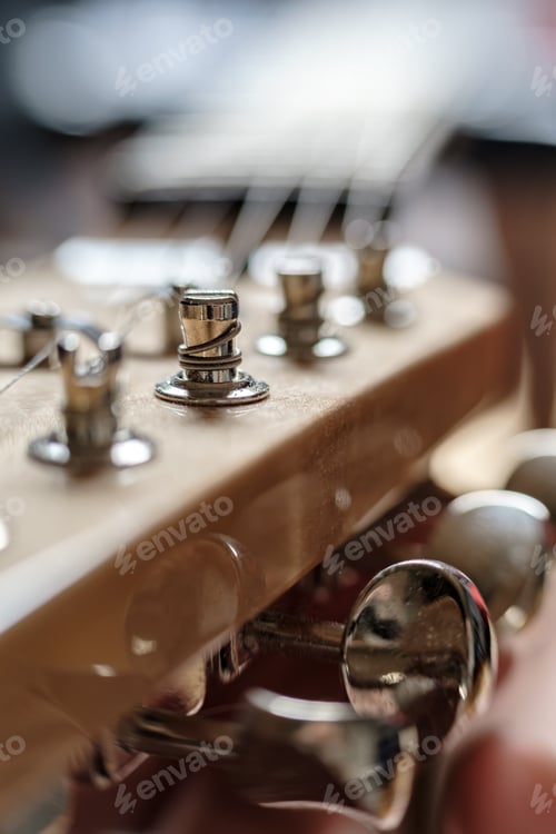Preview: String wound on a peg, close-up, on the headstock of an old wooden guitar