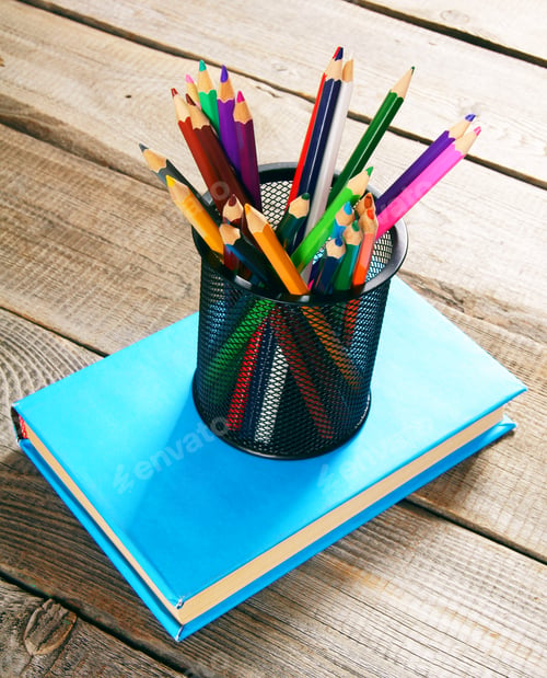 Preview: Pencils and book . On wooden background.