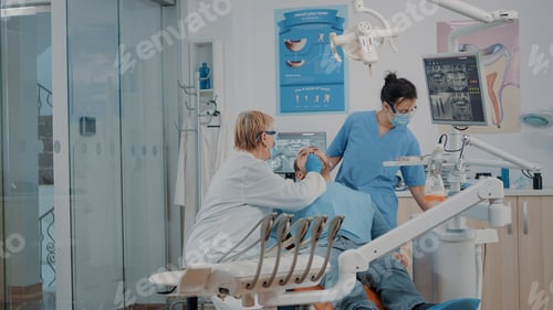 Preview: Dentist and nurse examining teeth of patient in dentistry cabinet