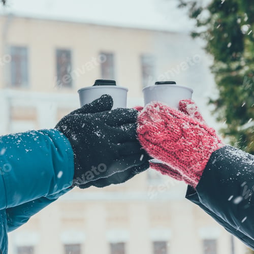 Preview: cropped shot of couple holding thermocups with hot drinks on street in winter