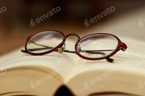 Preview: Glasses Resting on Open Book in Home Setting