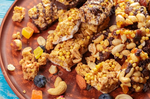 Preview: Snack bars made with nuts and dried fruits on a wooden plate in a bright kitchen